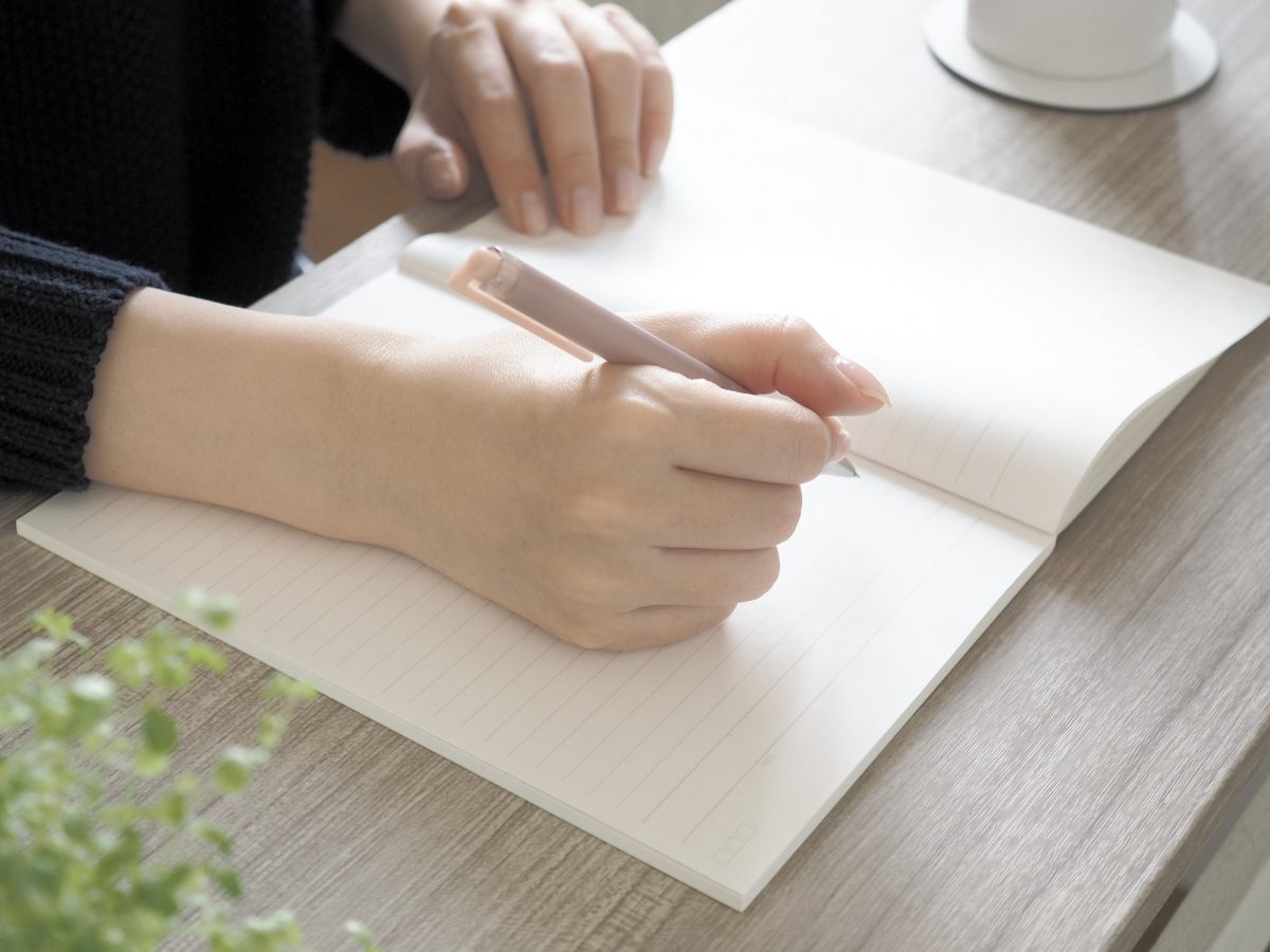 ノートにペンで書き留める手元